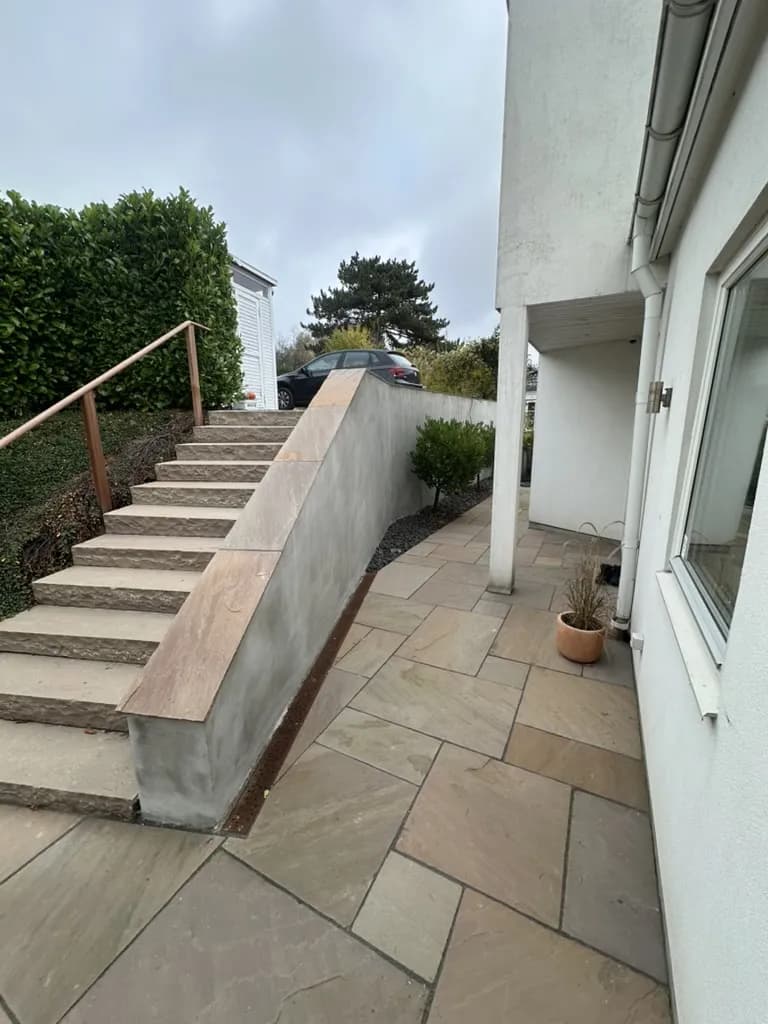 Natursten trappe - Sandstensbelægning med hård fuge og præcist fald. Trappen forbinder terrasse med have i et naturligt og holdbart design.